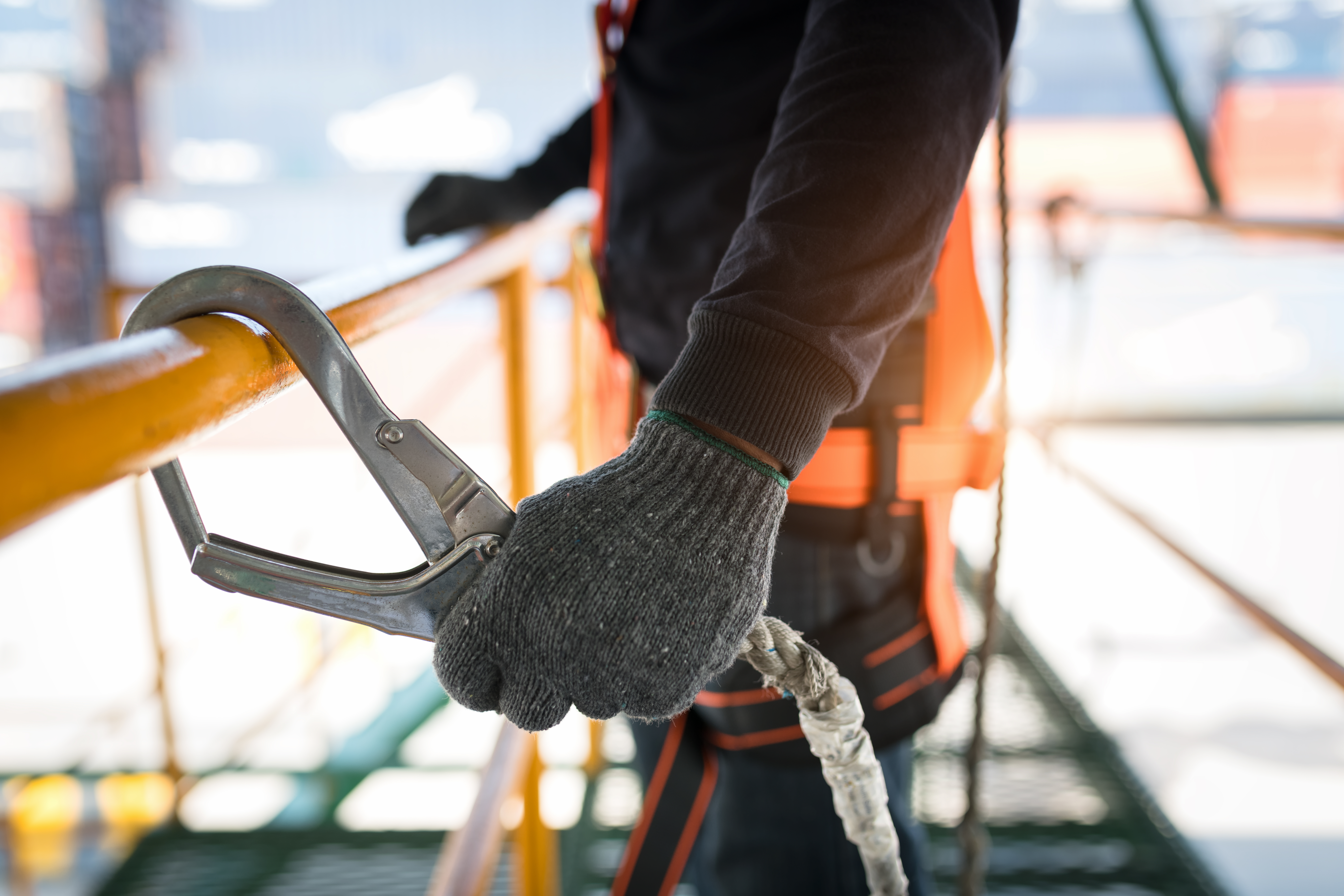 An industrial construction worker holding a harness